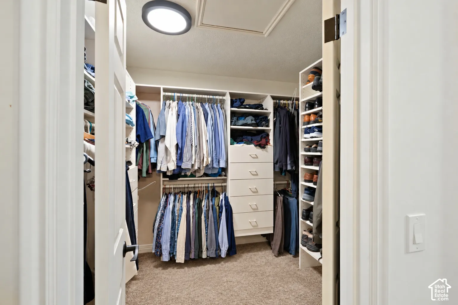 Walk-in closet featuring floor-to-ceiling built-in shelving, integrated dresser drawers, double-tier hanging rods, and a circular flush-mount ceiling light