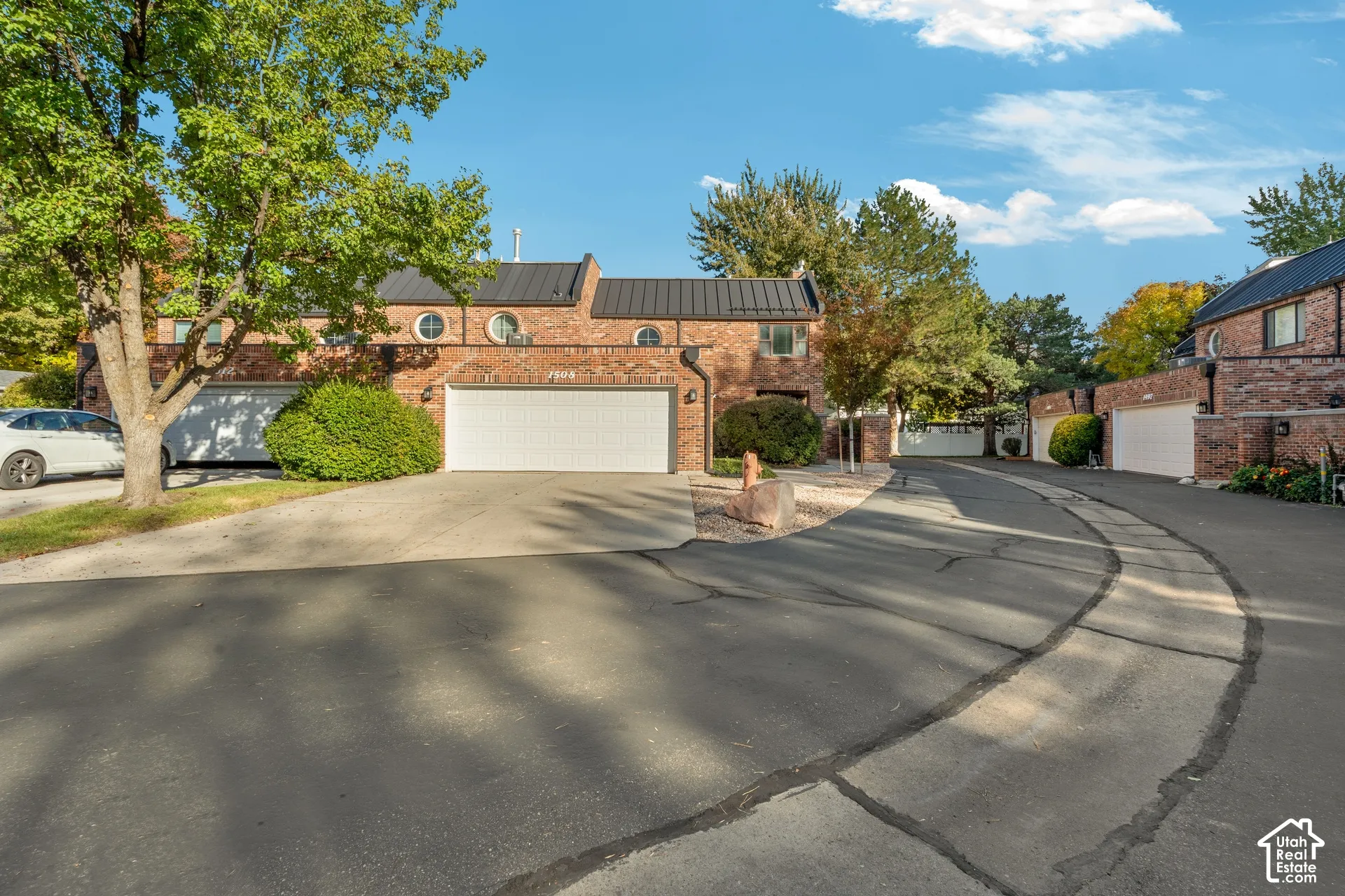 Brick exterior featuring a standing-seam metal roof, circular accent windows, and multi-car garage doors