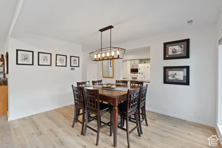 Dining space featuring wood-finish flooring, a tray ceiling, and a geometric multi-bulb hanging light fixture
