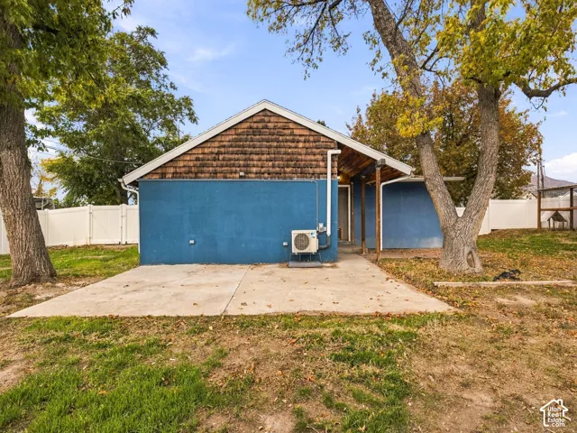 Exterior rear elevation featuring shake-shingle gable siding, concrete patio, and white vinyl privacy fencing