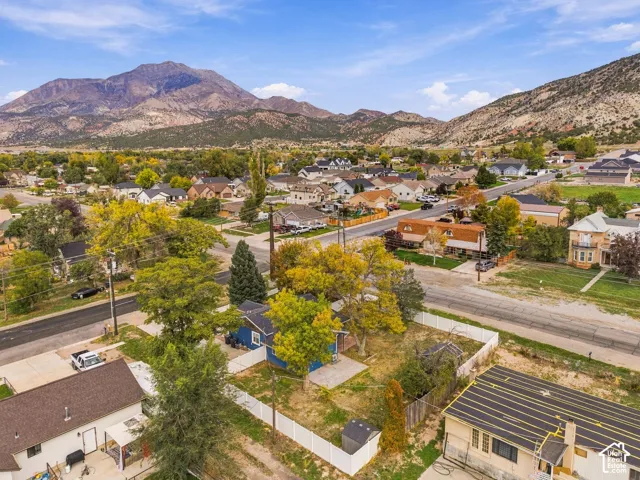 Aerial perspective of property featuring a white privacy fence, mature trees, and mountainous topography