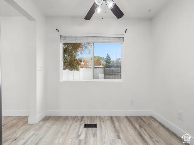 Neutral-toned wall finish, wood-finish flooring, sliding window with horizontal blinds, and a ceiling fan with integrated lighting