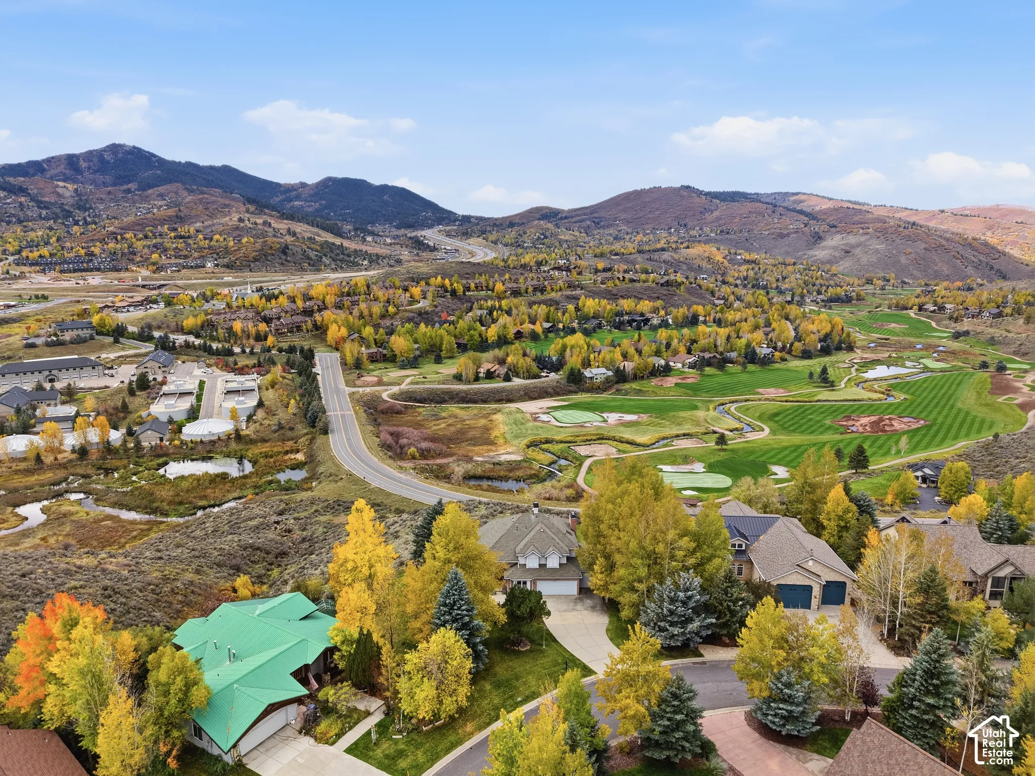 Aerial perspective showcasing mountain range, established trees, and proximity to golf course fairways