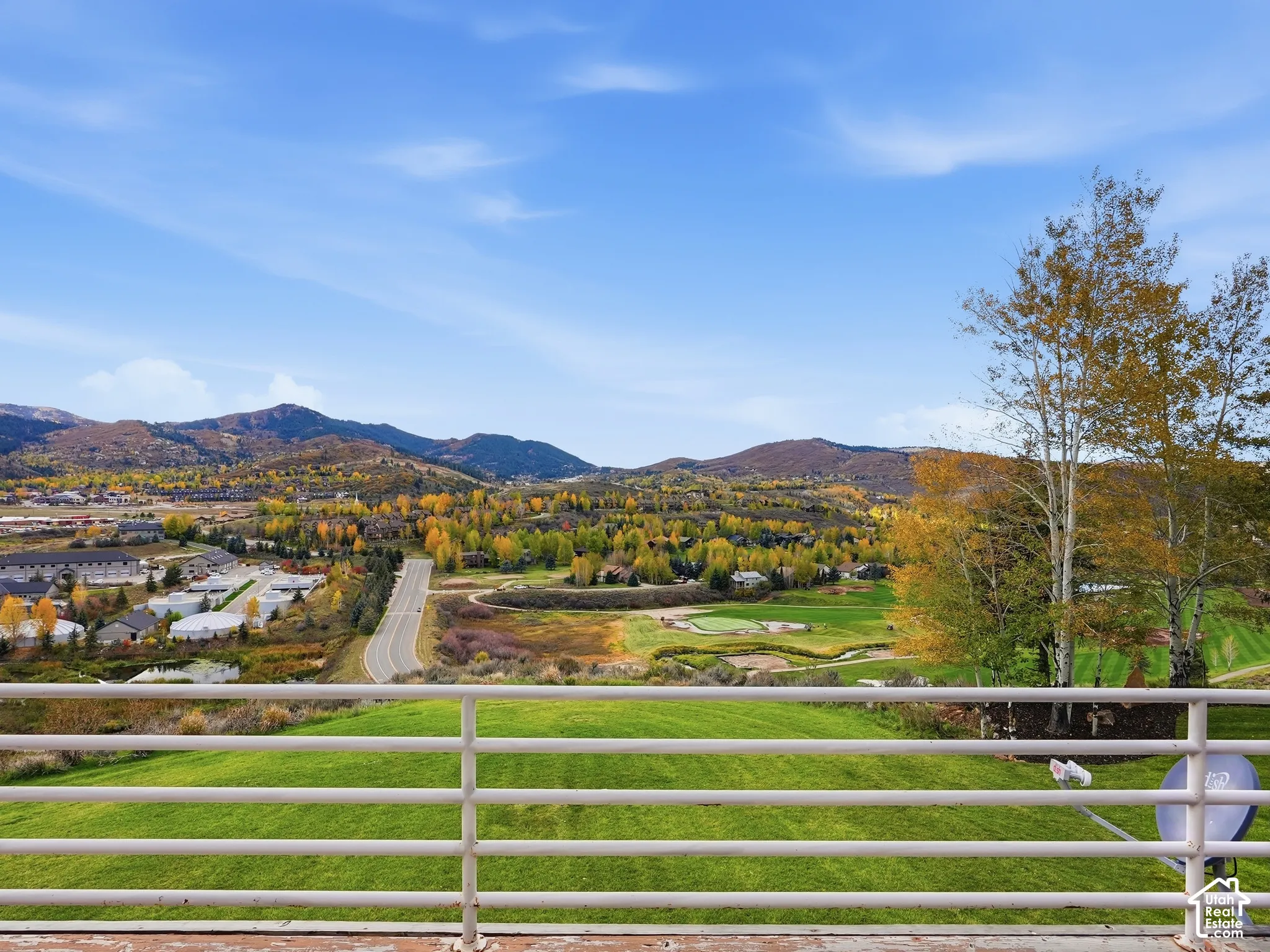 Elevated exterior railing overlooking a expansive manicured lawn, mature trees, and distant mountain topography