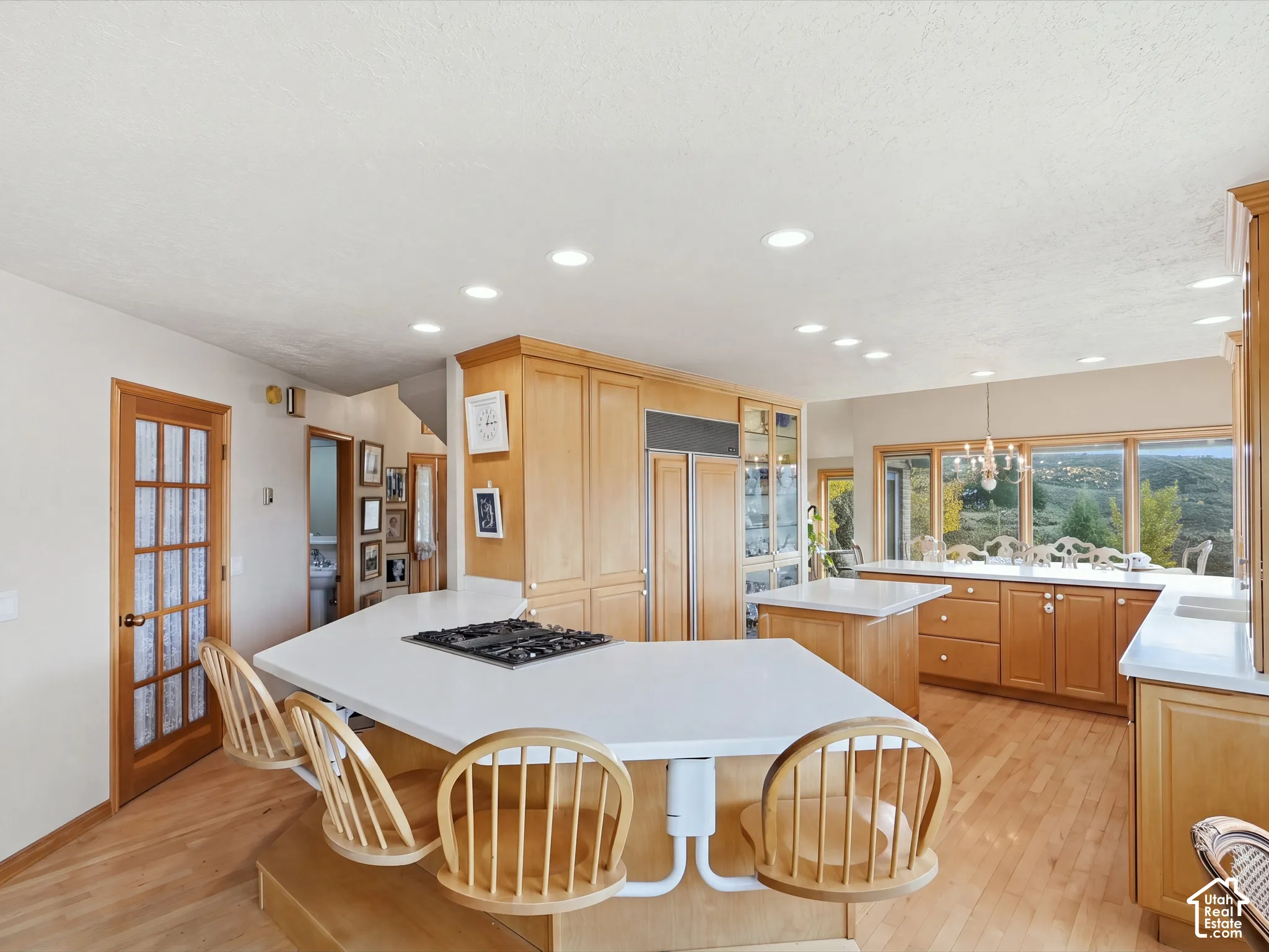 Kitchen featuring light wood cabinetry, white countertops, a multi-level breakfast bar with an integrated gas cooktop, recessed lighting, and wood-finish flooring