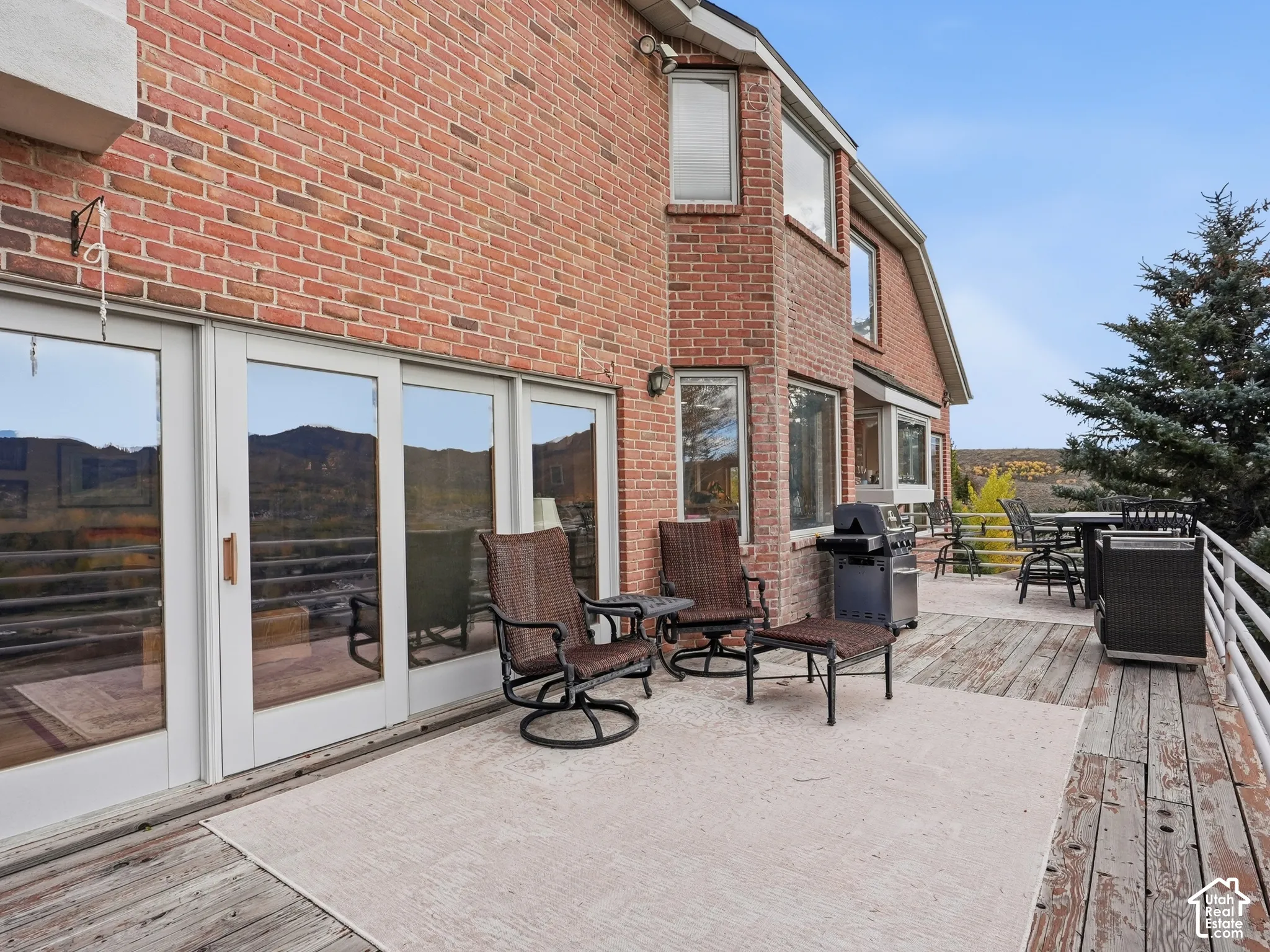 Exterior brick facade featuring expansive sliding glass doors and a sprawling wooden deck with metal railing