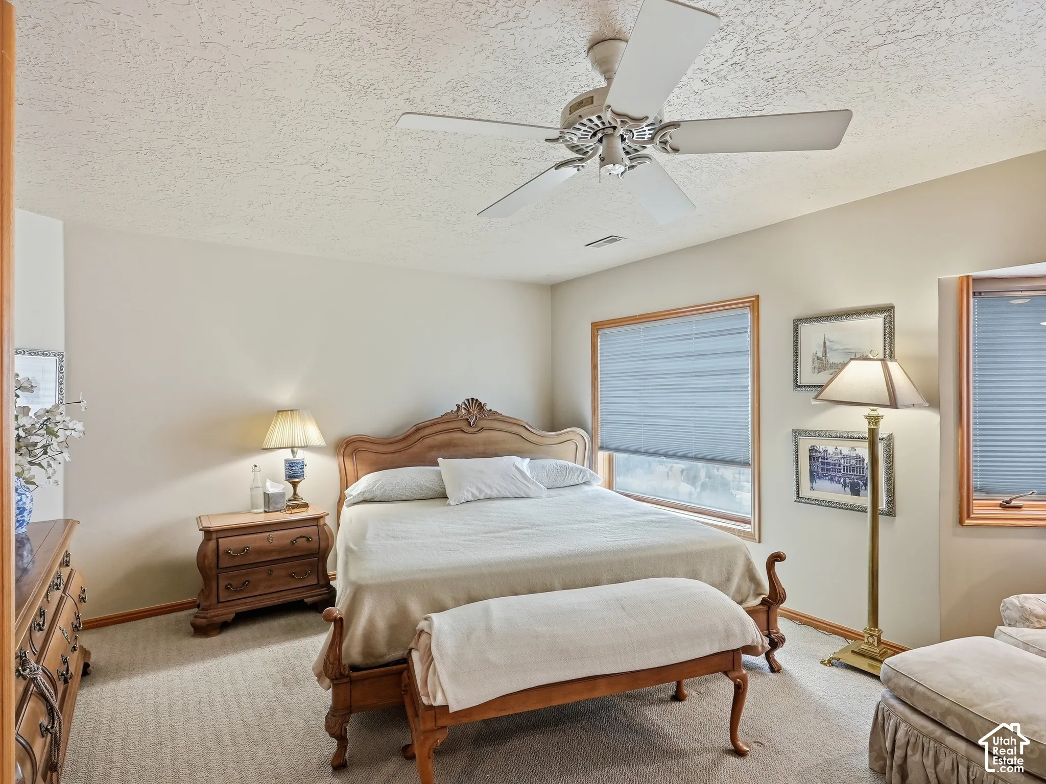 Neutral interior featuring light-toned wall paint, neutral carpeting, a ceiling fan with light fixture, and wooden window casings