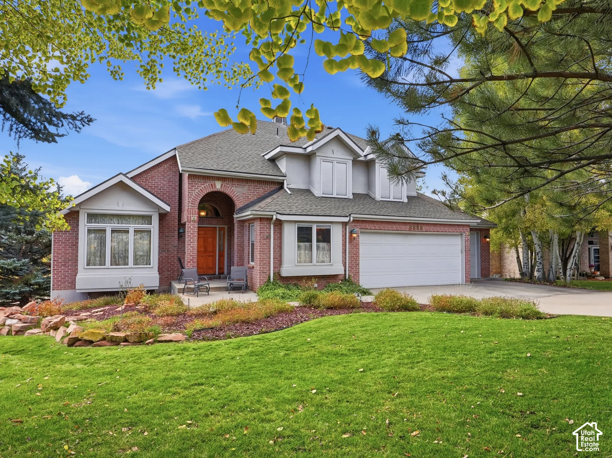 Multi-level brick exterior featuring a multi-gabled roofline, an arched entryway, bay windows, and a multi-car garage