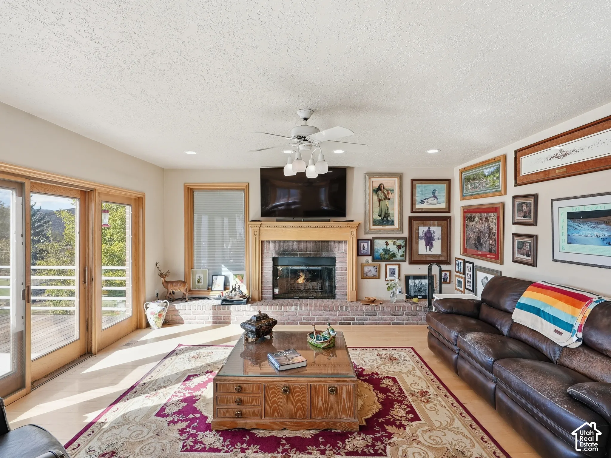 Brick fireplace with a wood mantel, light-toned flooring, recessed lighting, and sliding glass doors