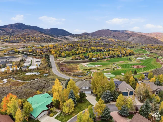 Aerial perspective showcasing mountain range, established trees, and proximity to golf course fairways