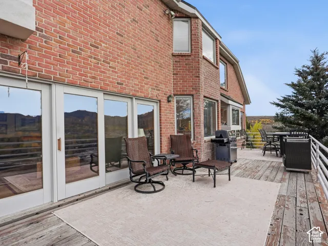 Exterior brick facade featuring expansive sliding glass doors and a sprawling wooden deck with metal railing