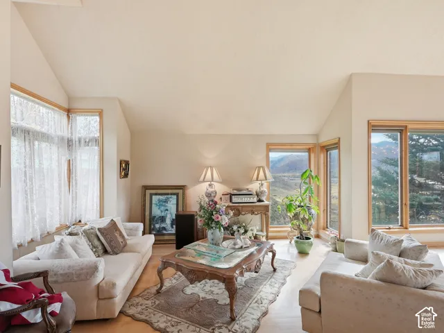 Vaulted ceilings featuring expansive windows with natural light, wood-finish flooring, and a mountainous landscape backdrop