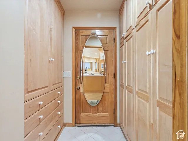 Built-in light-tone wood cabinetry featuring full-height storage, integrated drawers, and circular hardware, centered by a solid wood entry door with an oval wall mirror