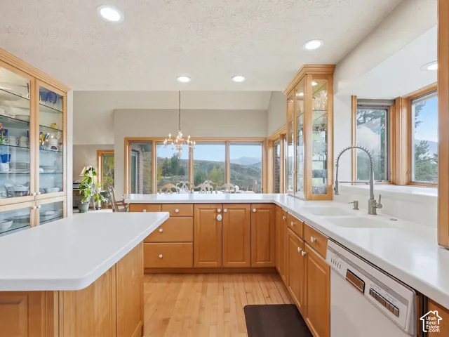 Kitchen featuring wood cabinetry, integrated glass-front display cabinets, solid-surface countertops, recessed lighting, and large windows with mountain scenery