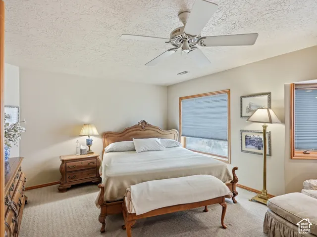 Neutral interior featuring light-toned wall paint, neutral carpeting, a ceiling fan with light fixture, and wooden window casings