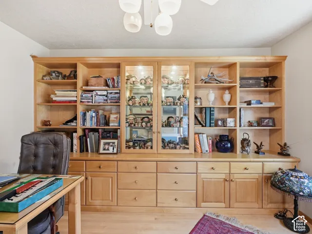 Wall-to-wall built-in cabinetry featuring light wood finish, adjustable shelving, glass-front display cabinets, and integrated lower drawers with round hardware