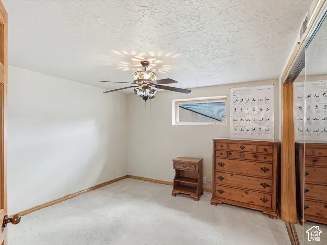 Room featuring neutral carpeting, a ceiling fan with decorative glass shades, and sliding mirrored closet doors