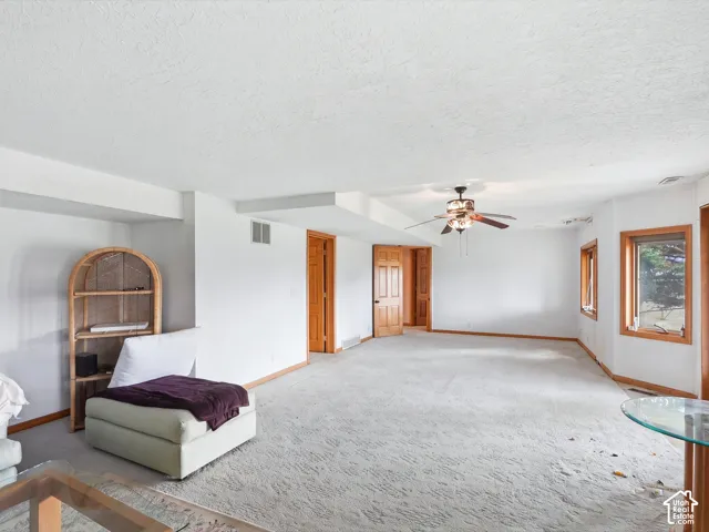 Spacious interior featuring wall-to-wall carpeting, wood-trim windows, six-panel wooden doors, and a ceiling fan with integrated lighting