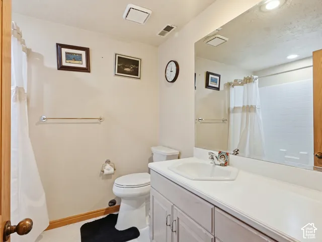 Bathroom featuring a white vanity with a molded basin, expansive wall-mounted mirror, polished chrome faucet, and a tub-shower combination with white tile surround