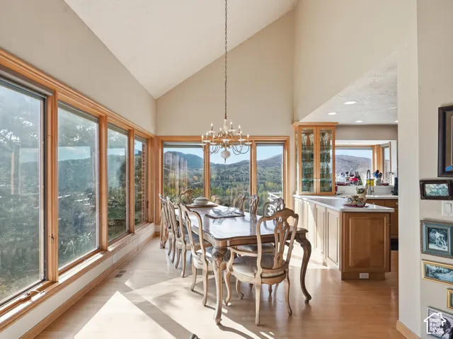 Vaulted ceilings, expansive windows, mountain backdrop, wood-finish flooring, and built-in glass-front cabinetry