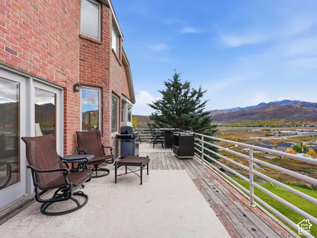 Red brick exterior wall, elevated wood decking, and metal railing overlooking a mountain landscape