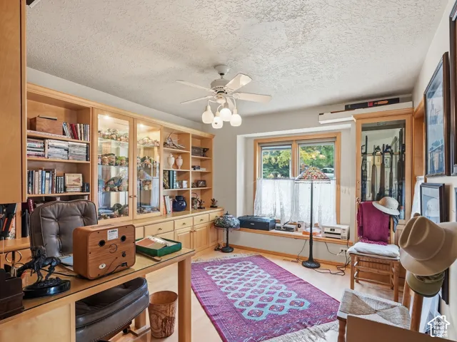 Built-in wood cabinetry with integrated glass-front display shelving, wood-finish flooring, bay window with bench seating, and ceiling-mounted fan with multi-light fixture