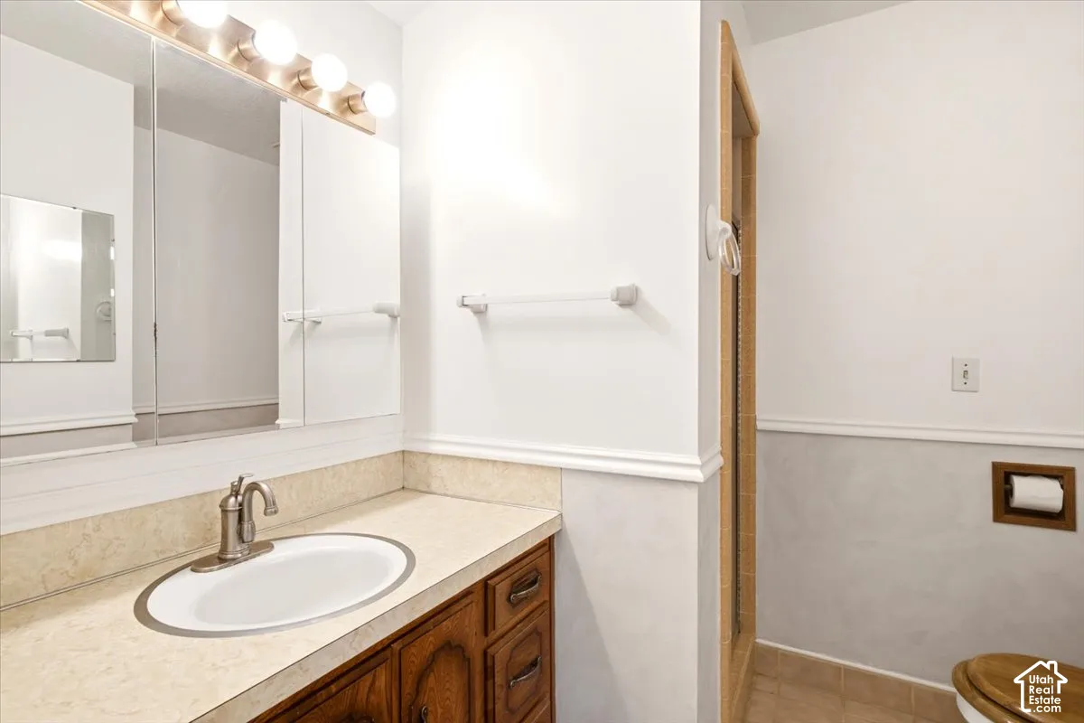 Bathroom vanity featuring a natural wood-finish cabinet, solid surface countertop with an integrated basin, brushed nickel faucet, and a multi-bulb vanity light fixture