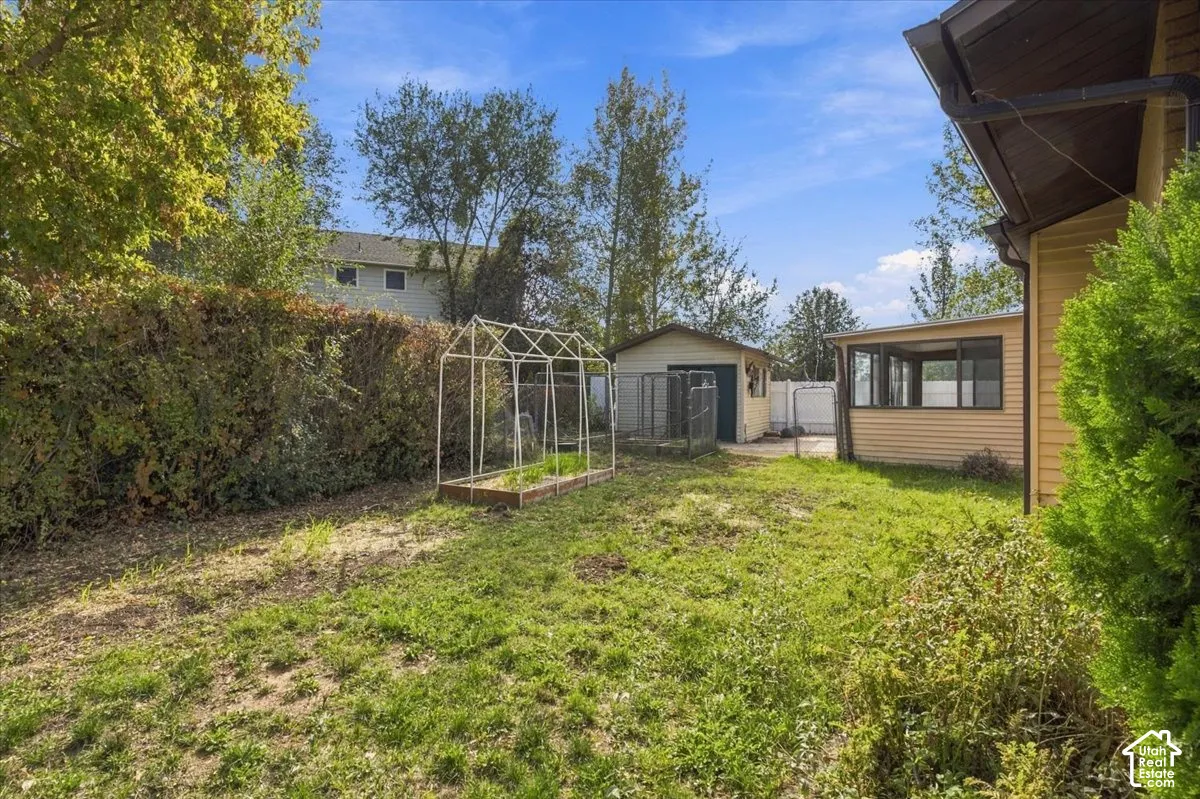 Rear yard featuring an enclosed sunroom, a detached storage structure, and a raised gardening frame