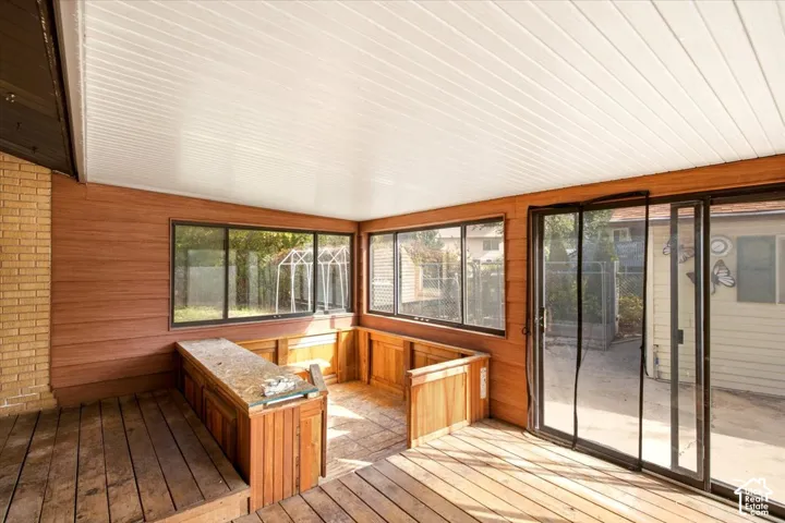 Enclosed patio featuring wood-paneled walls, tongue-and-groove ceiling, sliding glass doors, built-in wooden cabinetry, and wood-plank flooring