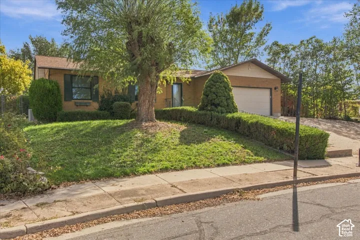 Single-story exterior featuring a brick facade, attached one-car garage, and manicured landscaping