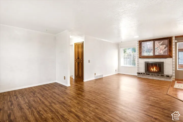 Living area featuring wood-finish flooring, a masonry fireplace with stone hearth, built-in wooden cabinetry, and large windows