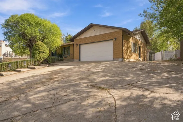Single-story residence featuring a tan brick exterior, gable roofline, two-car garage, and concrete driveway