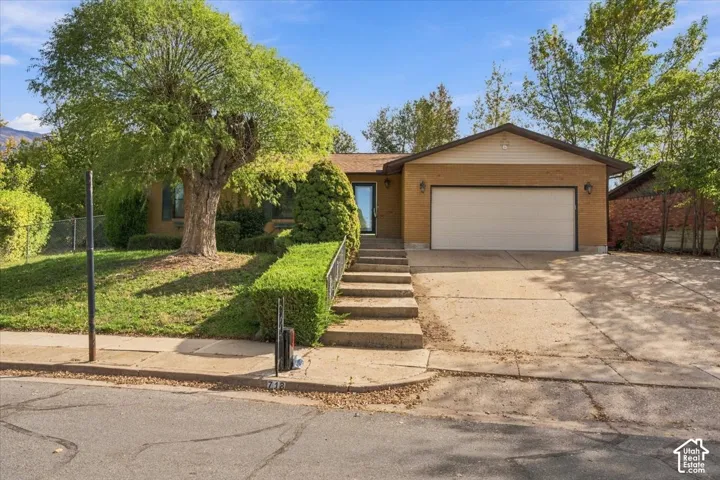 Single-story exterior featuring a brick facade, attached two-car garage, and concrete driveway