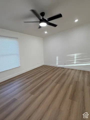 Neutral-toned room featuring wood-finish flooring, recessed lighting, and a modern matte black ceiling fan with integrated light