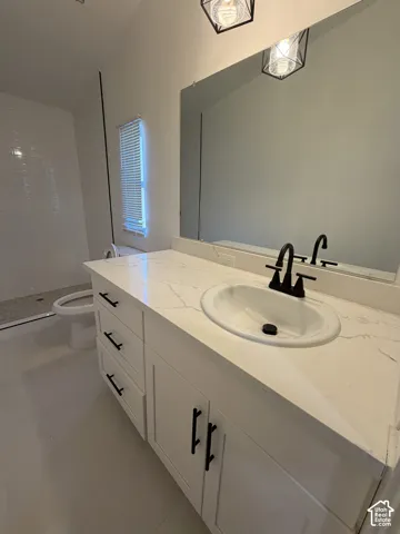 Bathroom vanity featuring white cabinetry, a stone-finish countertop with an integrated basin, matte black hardware, and geometric pendant lighting