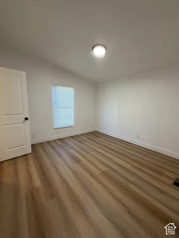 Neutral wall paint, wood-finish flooring, recessed ceiling lighting, and a single-panel interior door