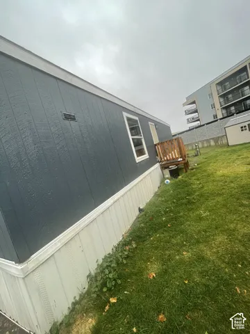 Exterior featuring blue vertical siding, light-toned skirting, an attached wood-frame deck, and a grass-covered lot