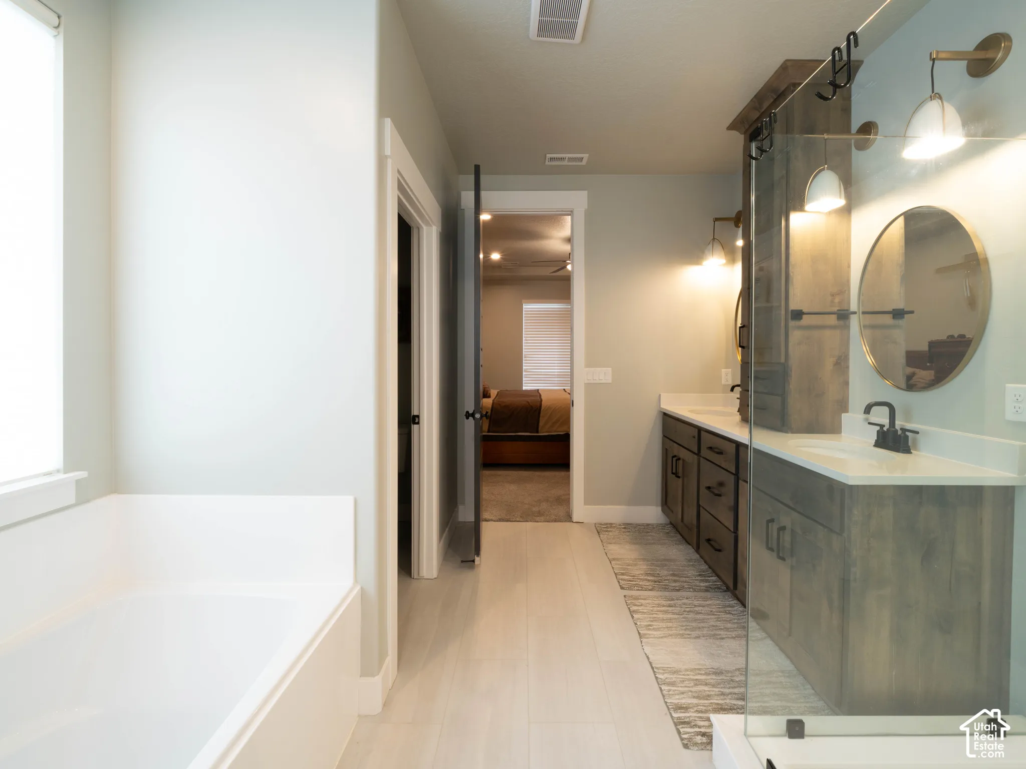 Primary ensuite bathroom. Dual vanity with undermount sinks, white countertops, and wood-finish cabinetry