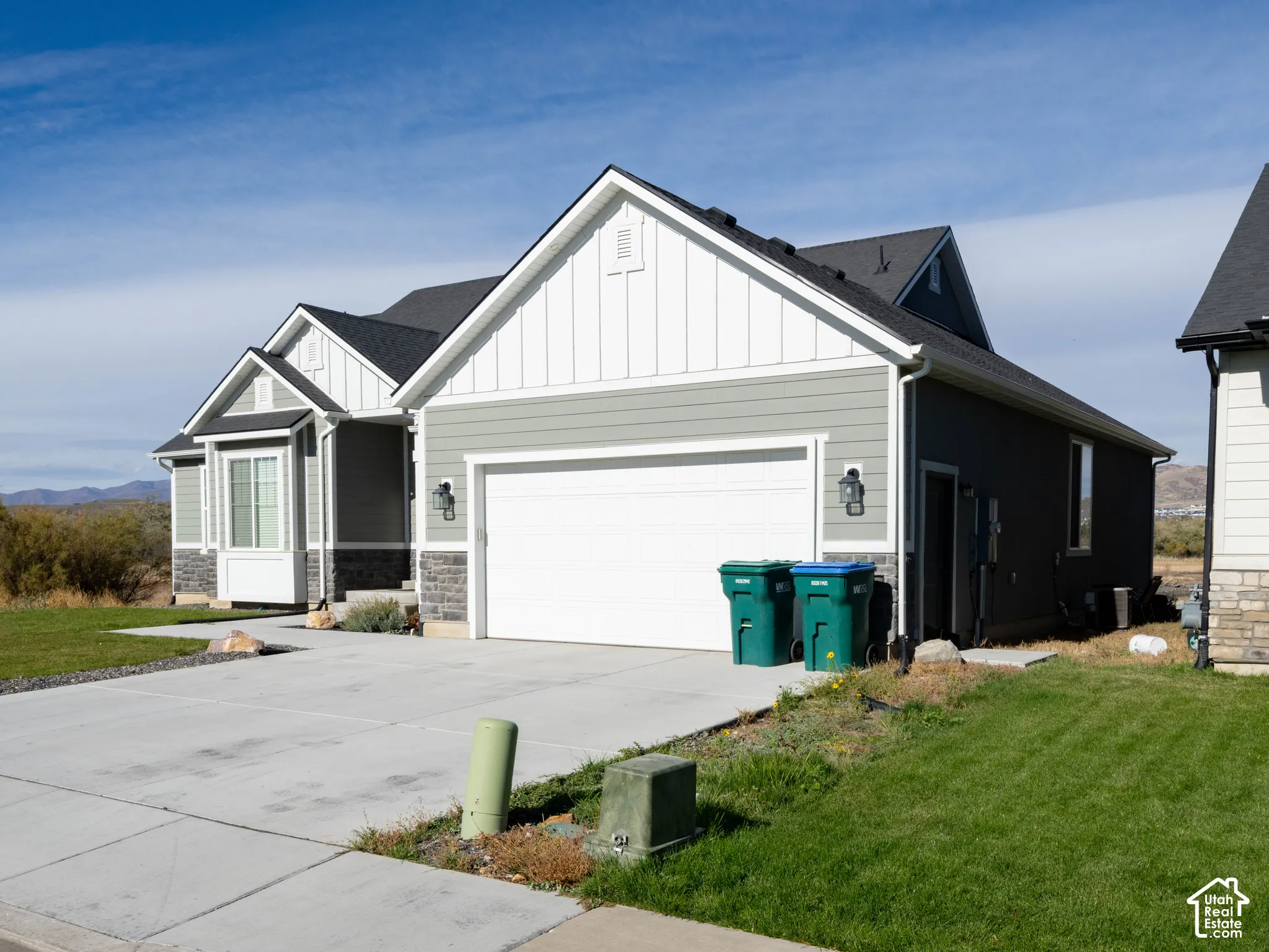 Exterior featuring a two-car garage, bay window, stone veneer accents, and a concrete driveway