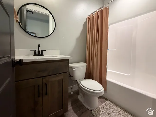 White solid surface vanity with integrated sink, dark wood-finish cabinetry, matte black fixtures, and a circular mirror