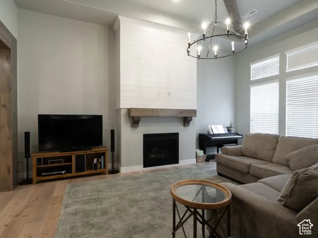 Vaulted ceiling with an exposed beam, wood-finish flooring, fireplace with a substantial wood mantel, and multiple large windows