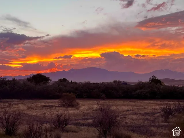 View from the backyard at sunset. Expansive open land featuring prominent mountain silhouettes and an orange-hued sunset