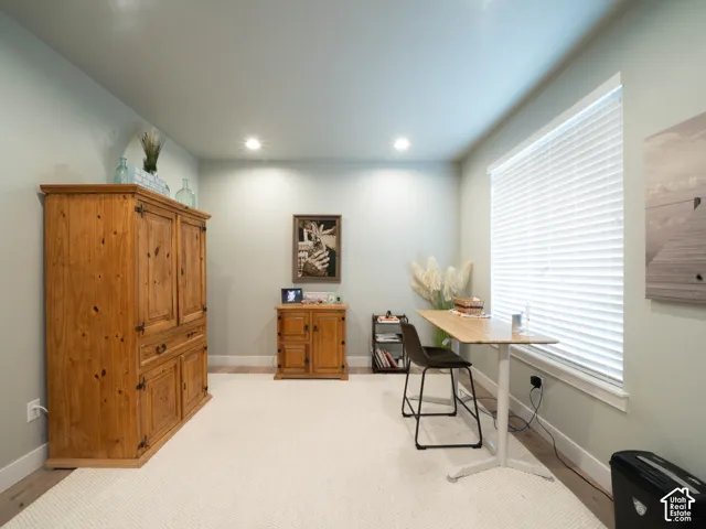 Recessed lighting, light-toned walls, wood-finish flooring, and a large window with blinds
