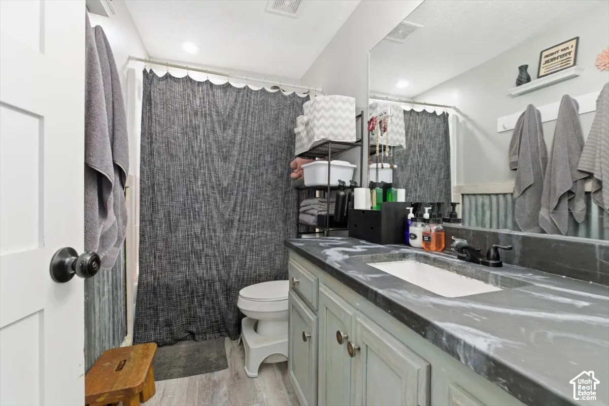 Bathroom vanity featuring a dark, veined stone countertop, an integrated rectangular sink, light-toned cabinetry, and matte black hardware, accented by corrugated metal wall paneling