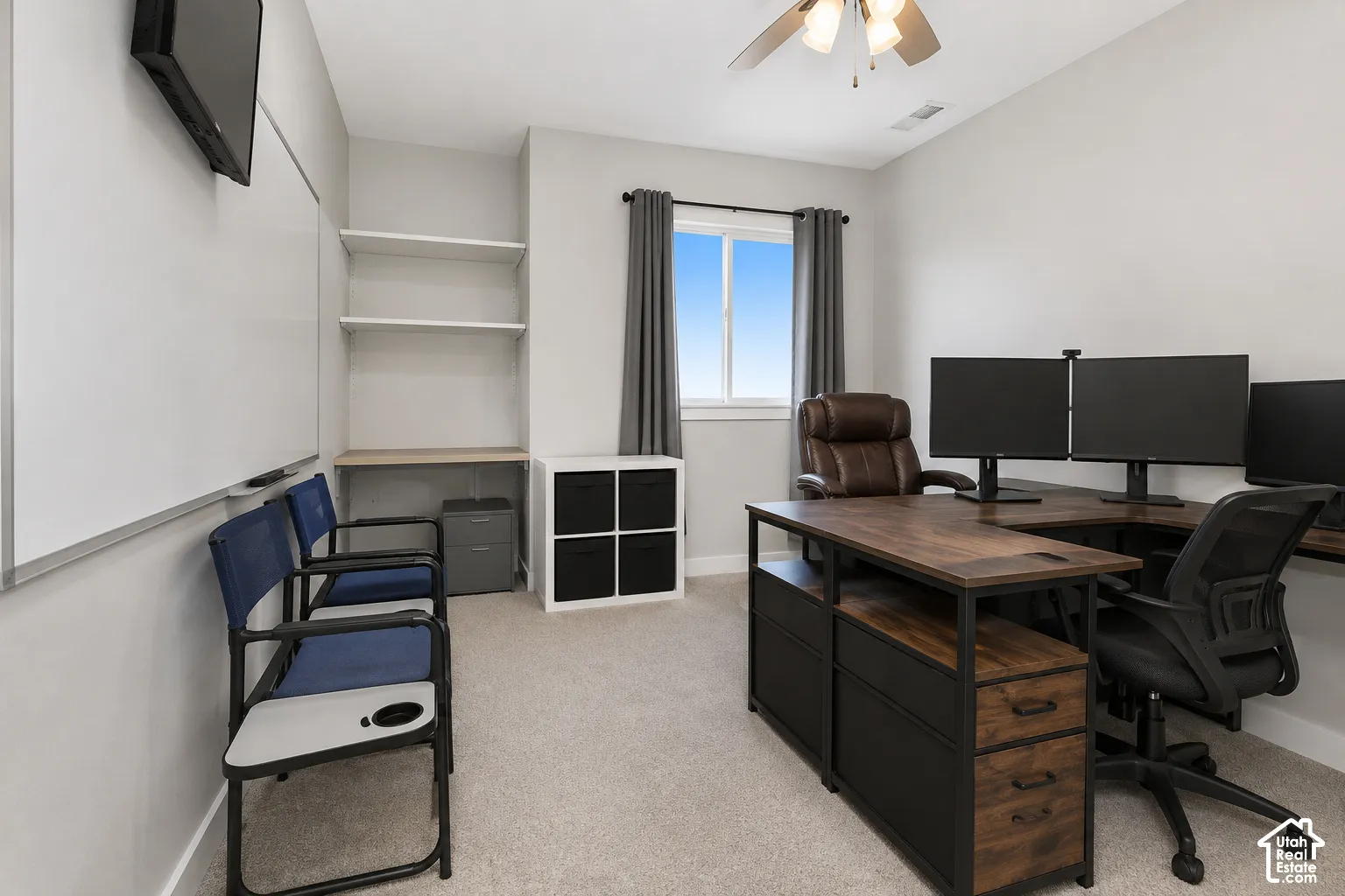 Room featuring neutral wall tones, carpeted flooring, a ceiling-mounted fan with light fixture, a single window, and built-in shelving