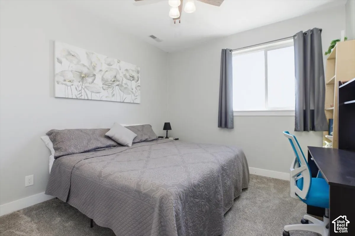 Neutral interior featuring grey carpeting, light-toned wall paint, a sliding window, and a ceiling-mounted light fixture with a fan