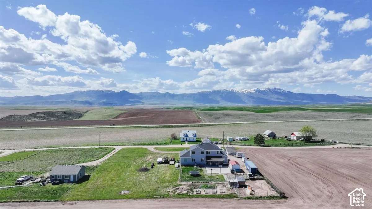 Aerial perspective of property featuring a multi-level residence, detached structure, expansive acreage, and prominent mountain backdrop