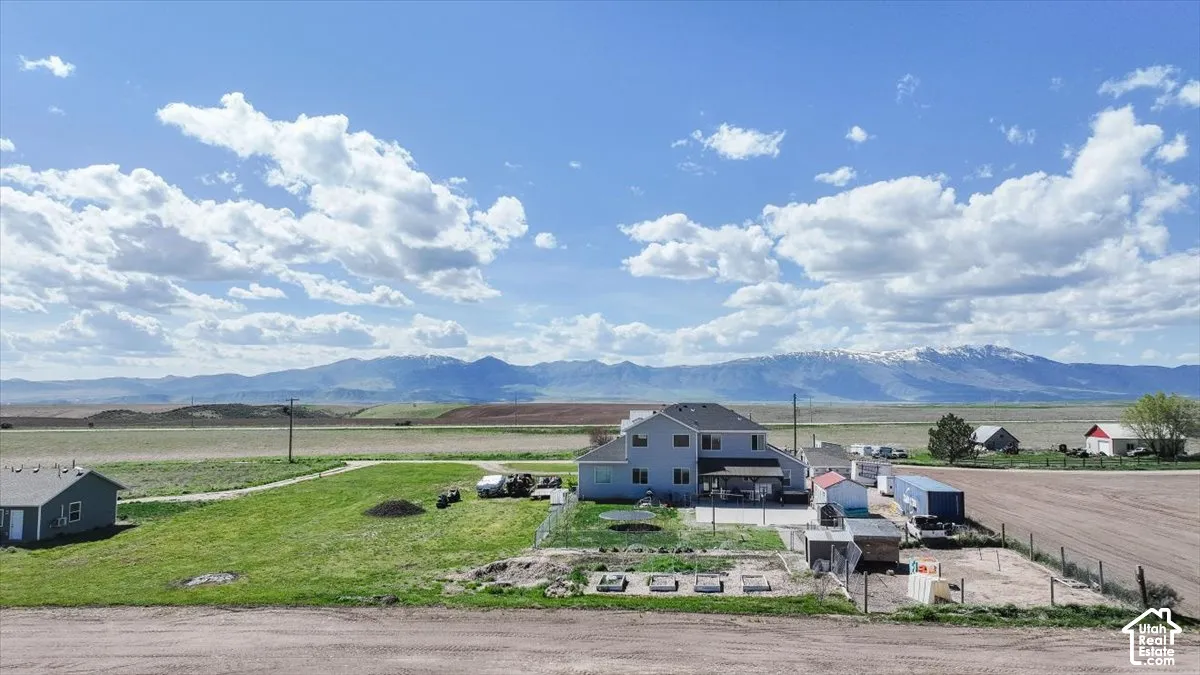Two-story residence featuring a paved patio, fenced grounds, and expansive mountain terrain