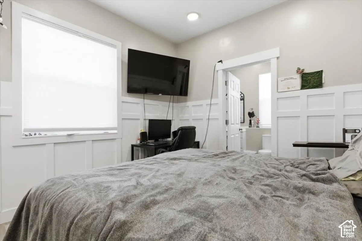 Room featuring crisp white wainscoting, neutral paint, recessed lighting, and a large window with roller shades