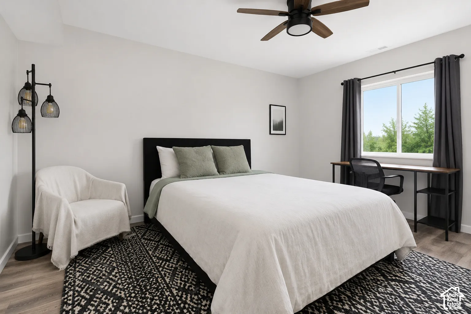 Neutral-toned interior featuring wood-finish flooring, a ceiling fan with integrated lighting, and a large window